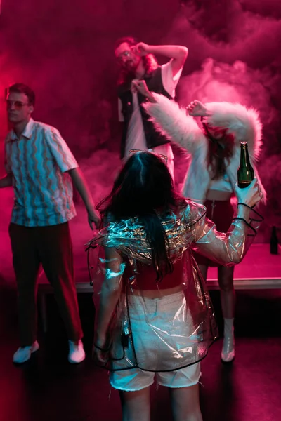 Hombres y niñas bailando en discoteca con humo rosa - foto de stock