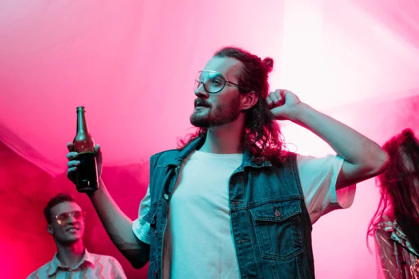 Hombre guapo sosteniendo cerveza en el club nocturno y bailando durante rave — Stock Photo