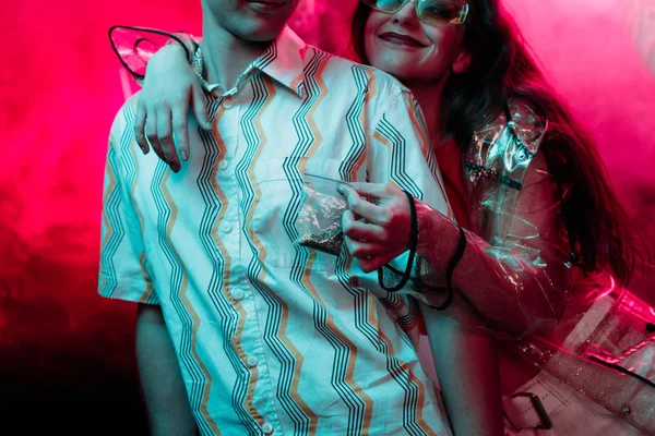 Обрізаний вид дівчини, що тримає бур'ян у поліетиленовому мішку блискавки біля чоловіка в нічному клубі — стокове фото