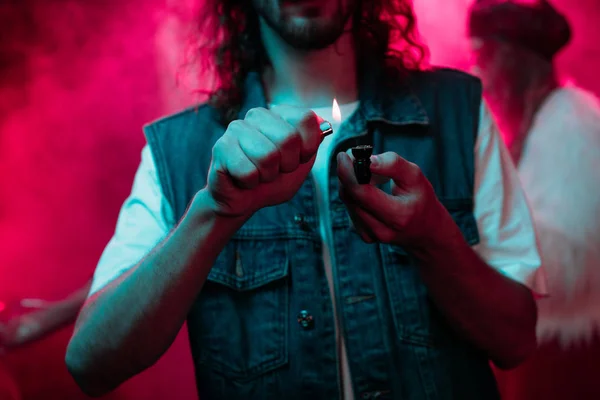 Recortado vista de hombre iluminación fumar pipa con marihuana en discoteca - foto de stock