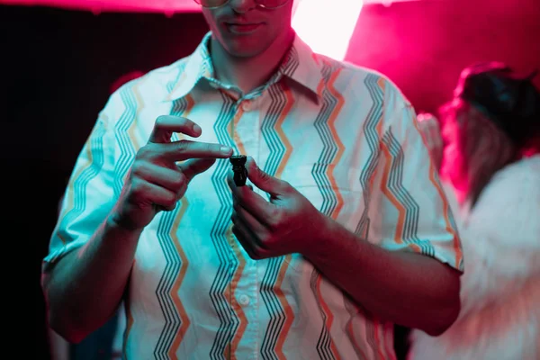 Vista recortada del hombre sosteniendo pipa de fumar con marihuana en el club nocturno - foto de stock