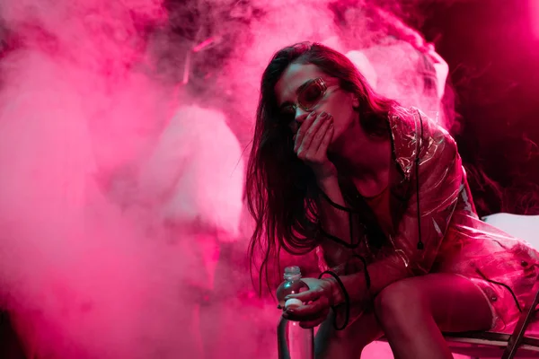 Krankes Mädchen sitzt mit Wasserflasche in Nachtclub — Stockfoto