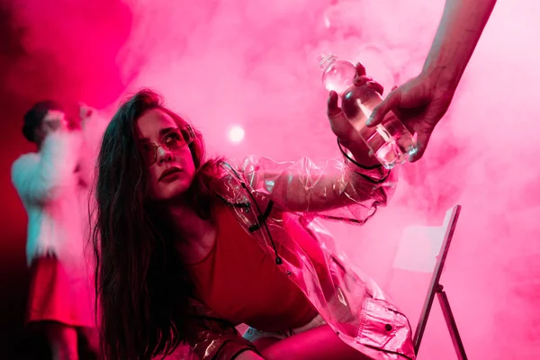 Sick young woman taking bottle of water in nightclub — Stock Photo