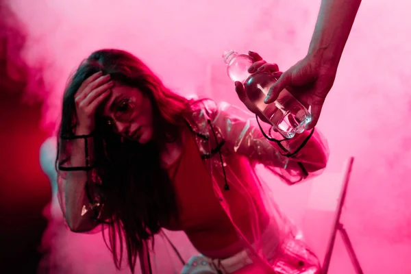 Chica enferma dolor de cabeza tomando botella de agua en el club nocturno — Stock Photo
