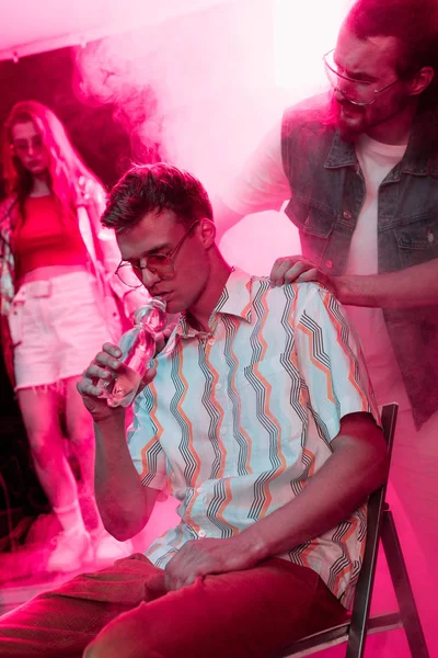 Man checking on sick man drinking water in nightclub — Stock Photo