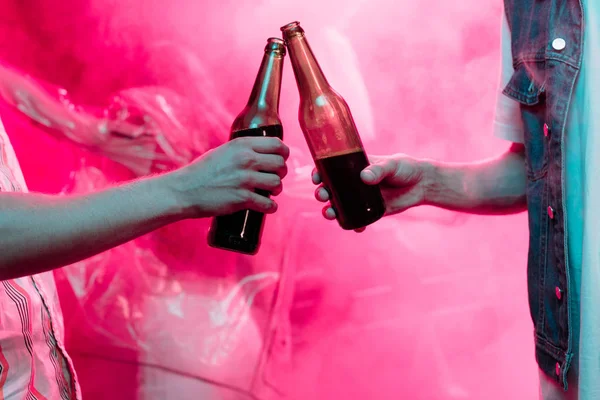 Vista recortada de los hombres tintineo con botellas de cerveza en discoteca - foto de stock