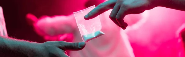 Panoramic shot of man passing drugs in plastic zipper bag to man in nightclub — Stock Photo