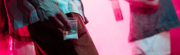 Panoramic shot of man holding drugs in plastic zipper bag in nightclub — Stock Photo