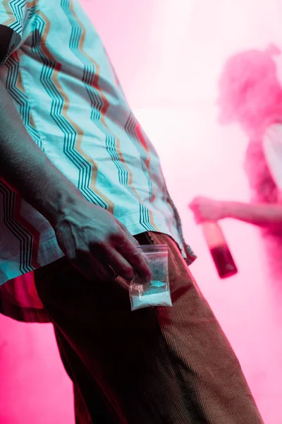 Partial view of man holding in hand drugs in plastic zipper bag in nightclub — Stock Photo