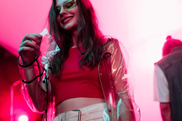 Улыбающаяся девушка держит пластиковый пакет с молнией с наркотиками в ночном клубе — стоковое фото