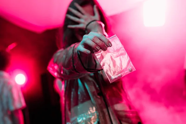 Mädchen hält Plastiktüte mit Drogen in Nachtclub und verdeckt Gesicht — Stockfoto