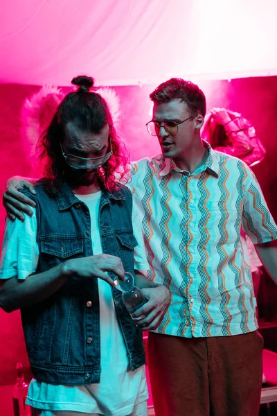 Man hugging another man with water bottle in nightclub during rave party — Stock Photo