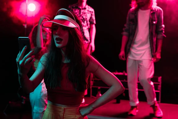 Девушка делает селфи на смартфоне во время вечеринки в ночном клубе — стоковое фото