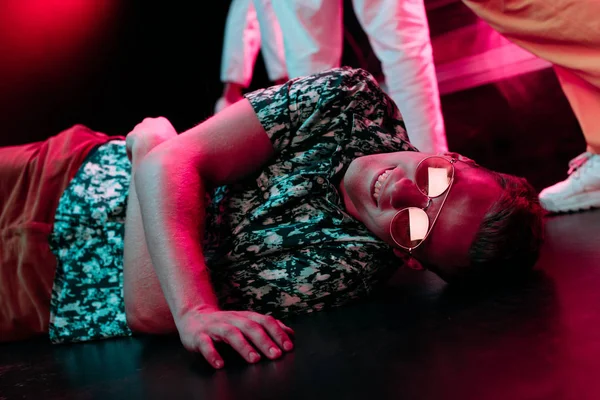 Hombre enfermo en gafas de sol tumbado en el suelo en discoteca - foto de stock