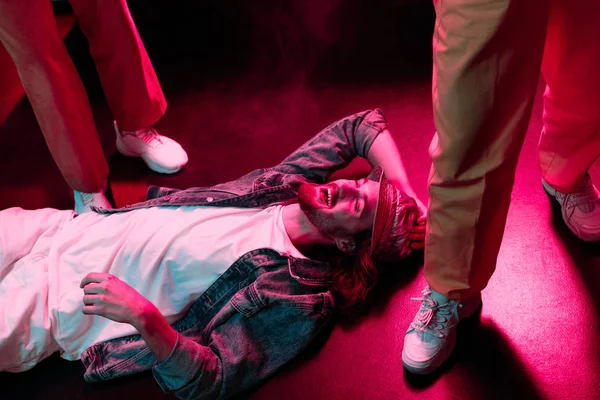 Smiling man lying on floor in nightclub with dramatic lighting — Stock Photo