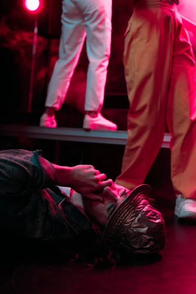 Sick man lying on floor in nightclub with dramatic lighting and covering mouth — Stock Photo