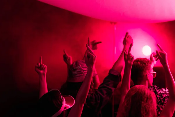 Visão traseira de pessoas com as mãos levantadas durante a festa rave em boate — Fotografia de Stock