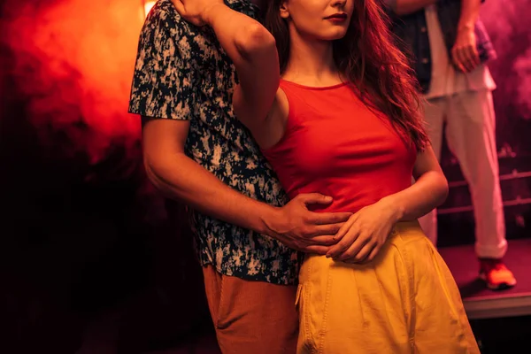 Cropped view of man hugging girl during rave party in nightclub — Stock Photo