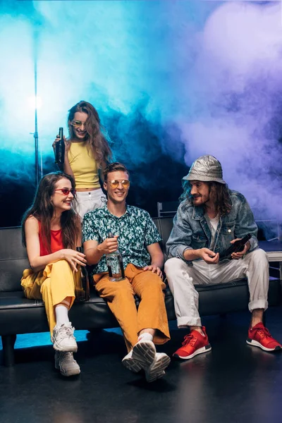 Jeunes femmes et hommes avec de l'alcool assis sur le canapé dans une boîte de nuit — Photo de stock