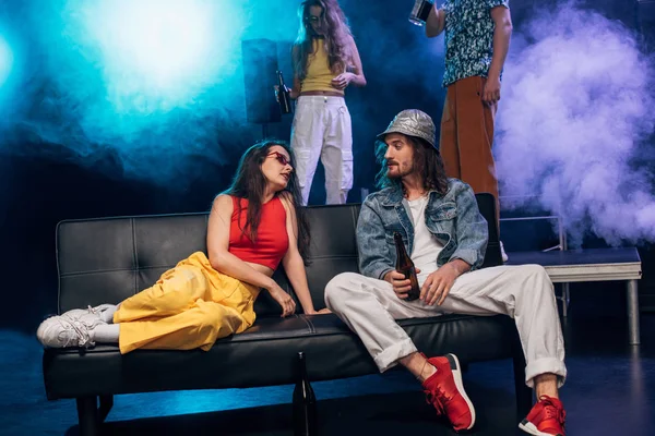 Man with alcohol and beautiful girl sitting on couch in nightclub — Stock Photo