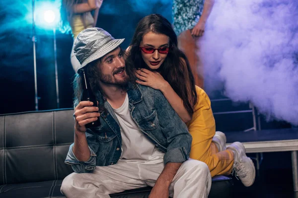 Homme avec de l'alcool et belle fille assise sur le canapé dans la boîte de nuit — Photo de stock