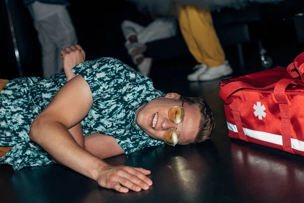 Homme couché sur le sol près du sac trousse de premiers soins dans la boîte de nuit — Photo de stock