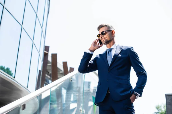 Handsome man in suit with hand in pocket talking on smartphone — Stock Photo