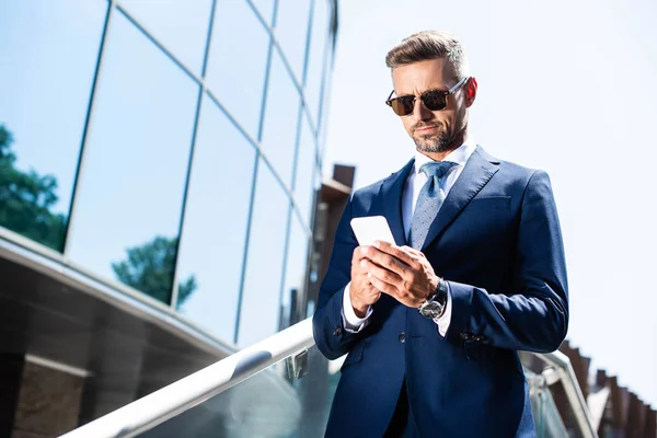 Homem bonito em terno e óculos usando dispositivo digital — Fotografia de Stock