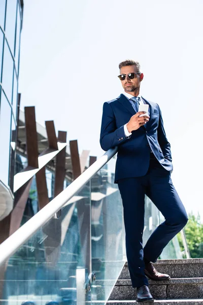 Bel homme en costume avec la main dans la poche en utilisant un smartphone — Photo de stock