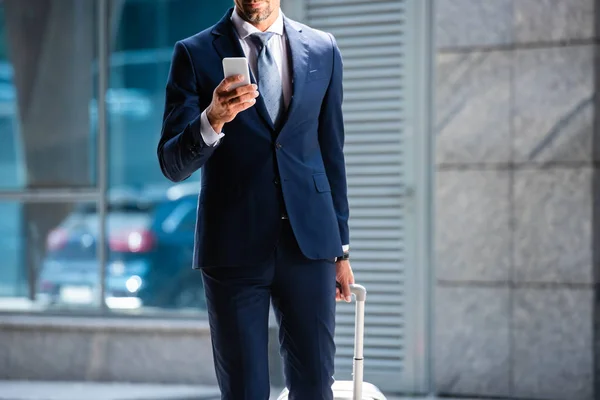 Vista recortada del hombre en traje usando el teléfono inteligente exterior - foto de stock