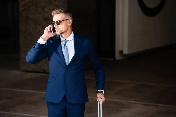 Handsome businessman in suit and glasses talking on smartphone — Stock Photo