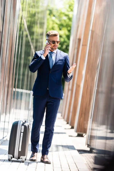 Hombre de negocios guapo en traje y gafas hablando en smartphone - foto de stock