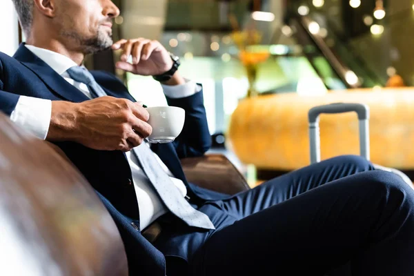 Recortado vista de guapo hombre de negocios en traje celebración taza - foto de stock