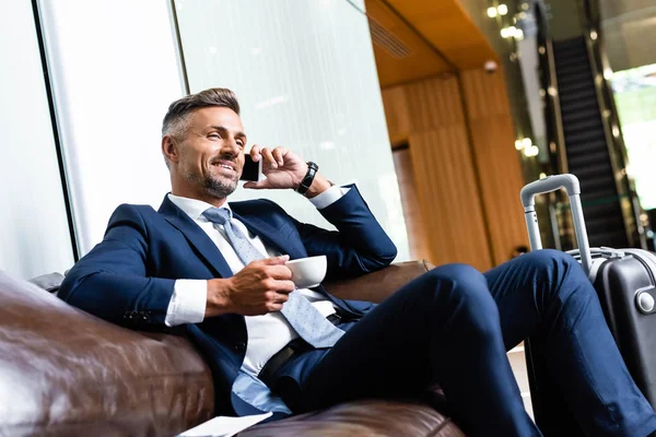 Bell'uomo d'affari in giacca e cravatta che parla su smartphone e tiene la tazza — Foto stock