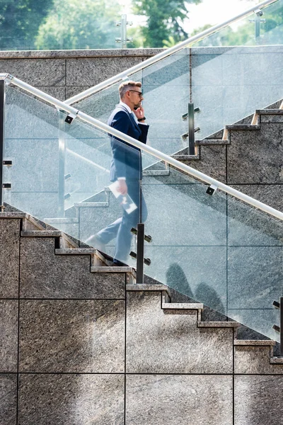 Homem de negócios bonito em terno e óculos falando no smartphone — Fotografia de Stock