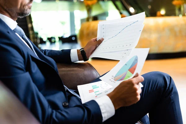 Cropped view of businessman in suit holding papers in hotel — Stock Photo