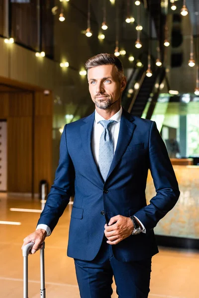 Gutaussehender und selbstbewusster Geschäftsmann im Anzug, der im Hotel wegschaut — Stockfoto