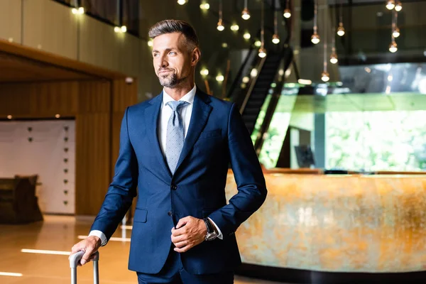 Gutaussehender und selbstbewusster Geschäftsmann im Anzug, der im Hotel wegschaut — Stockfoto