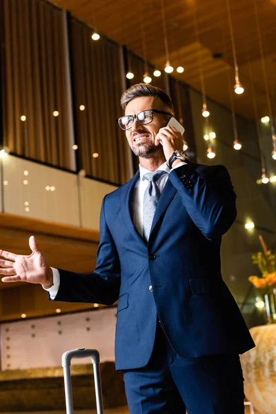 Красивый бизнесмен в костюме и в очках разговаривает на смартфоне — стоковое фото