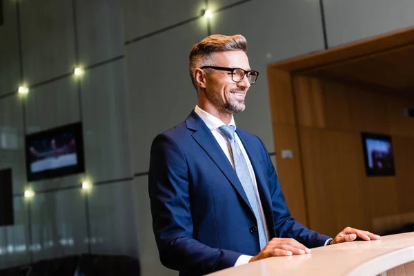Handsome businessman in suit and glasses smiling and looking away — Stock Photo