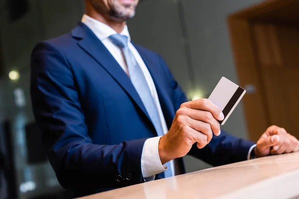 Vista recortada del hombre de negocios en traje dando tarjeta de crédito - foto de stock