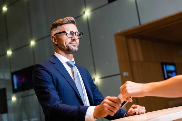 Gutaussehender Geschäftsmann in Anzug und Brille schenkt Frau Kreditkarte — Stockfoto