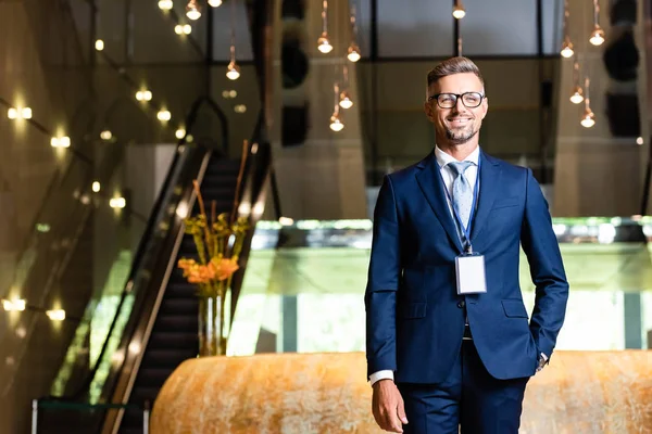 Uomo d'affari bello e sorridente in abito e occhiali con mano in tasca — Foto stock