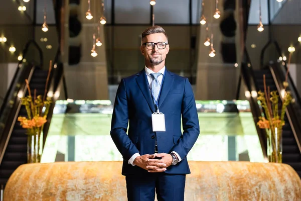 Hombre de negocios guapo en traje y gafas con placa en el hotel - foto de stock