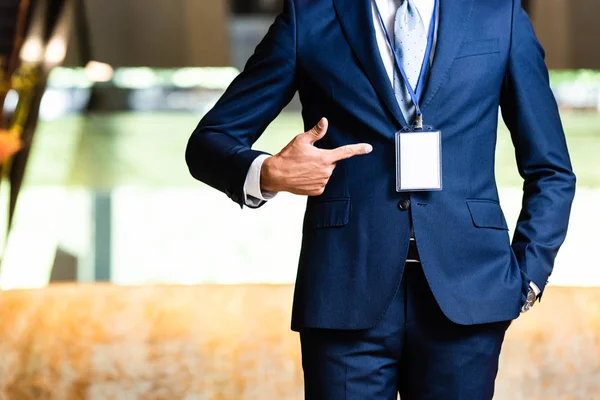 Vista recortada del hombre en traje apuntando con el dedo a la insignia - foto de stock