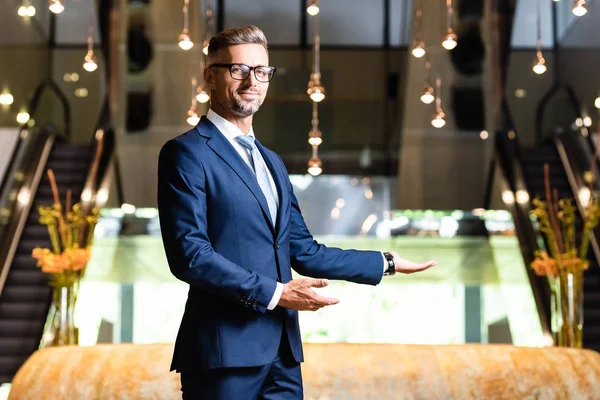 Homem de negócios bonito em terno e óculos apontando com as mãos — Fotografia de Stock