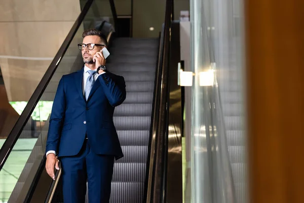 Handsome businessman in suit and glasses talking on smartphone — Stock Photo