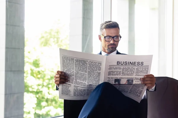 Bel homme d'affaires en costume et lunettes lecture affaires journal — Photo de stock