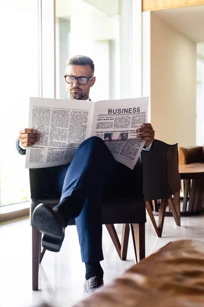 Bonito homem de negócios em terno e óculos lendo jornal negócio — Fotografia de Stock