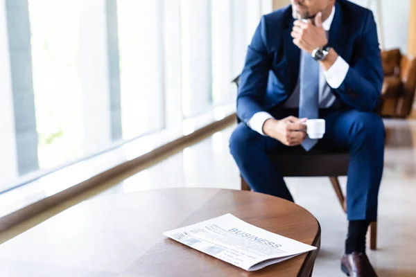 Vista recortada del hombre de negocios en traje que sostiene la taza en el hotel - foto de stock